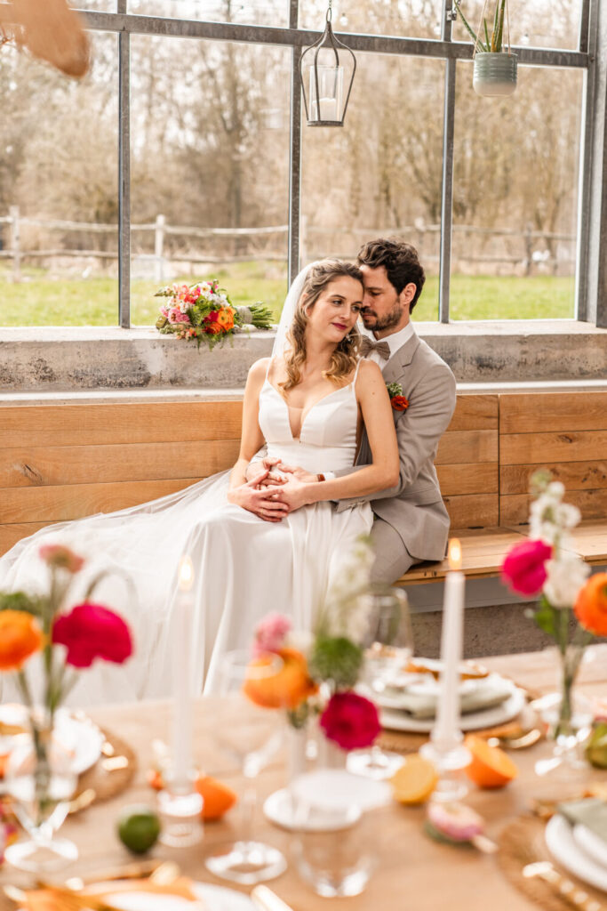 Brautpaar im Galanthus Piusheim an der Fensterbank – bunte Tischdekoration im Glashaus – Hochzeitsfotografin Maria Huber