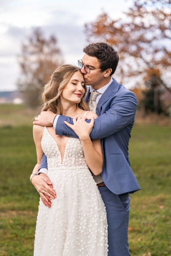Brautpaar umarmt sich herzlich im Herbst bei einem Hochzeitsshooting im Freien
