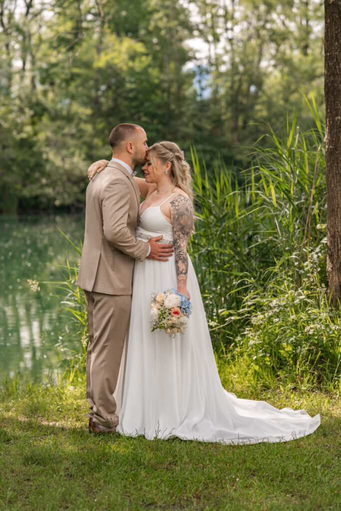 Brautpaar am See in der Natur – innig- Stirnkuss – Hochzeitsfotografie Maria Huber