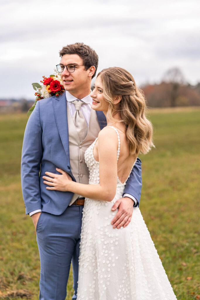 Brautpaar auf der Wiese beim Hofgut zur Mühle Holzham mit Blick ins Voralpenland – Hochzeitsfotografin Maria Huber Rosenheim
