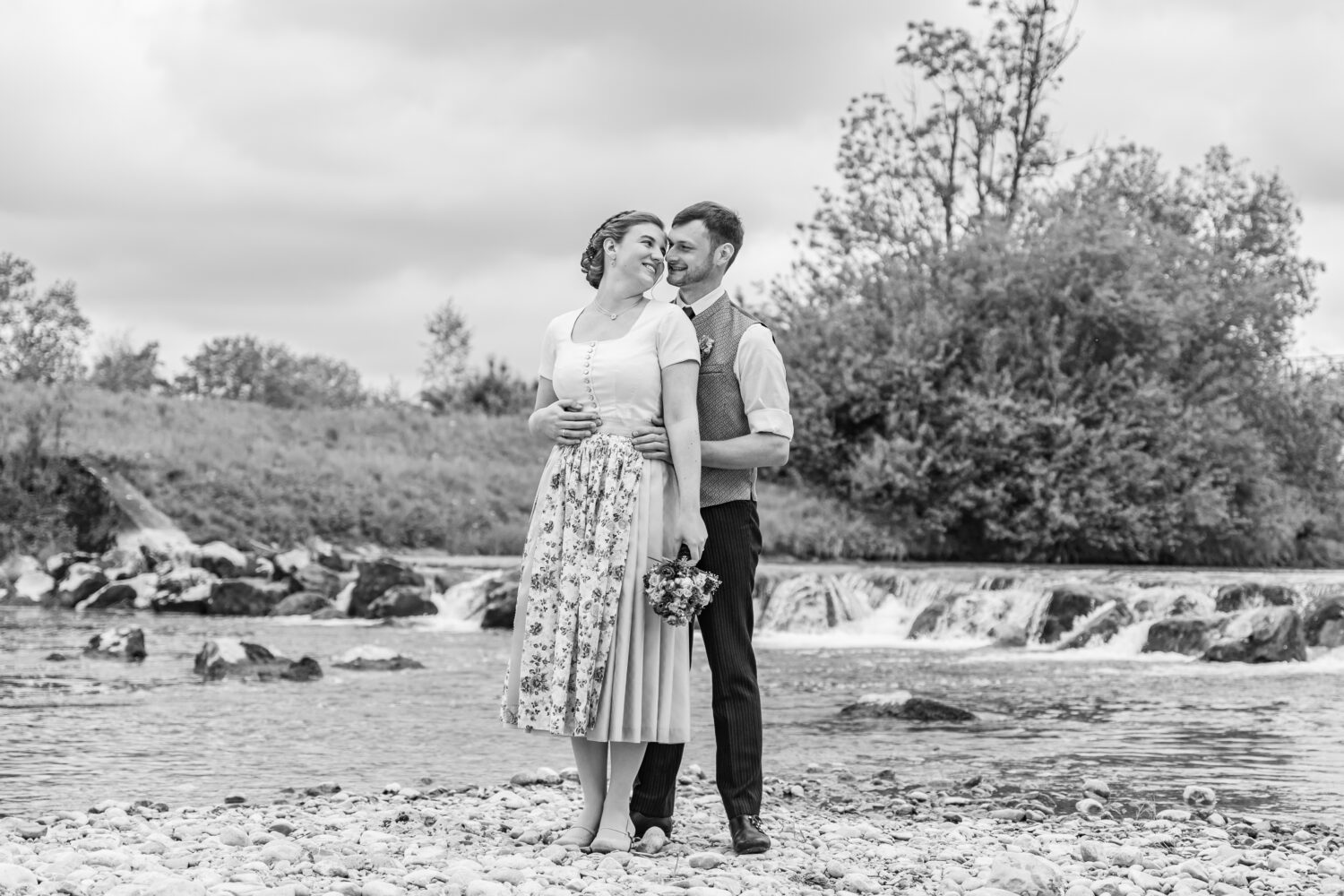 Brautpaar in Tracht am Fluss in Bayern – schwarzweiß – Hochzeitsfotografin Maria Huber Rosenheim