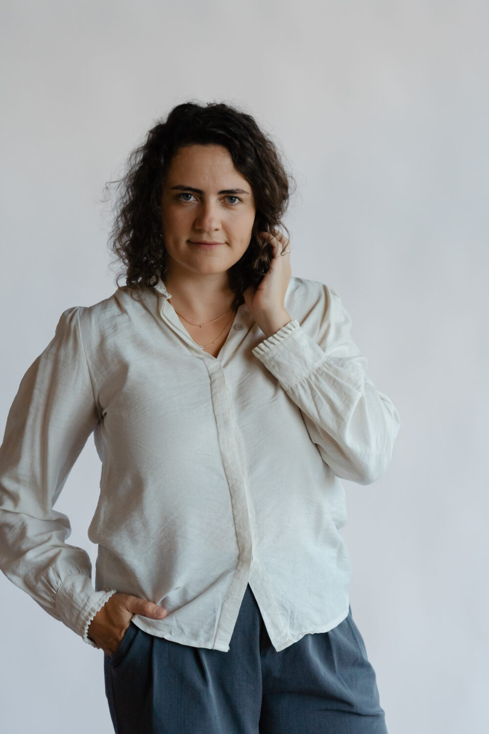 Maria Huber, Hochzeitsfotografin aus Bayern, Porträt vor neutralem Hintergrund in cremefarbener Bluse