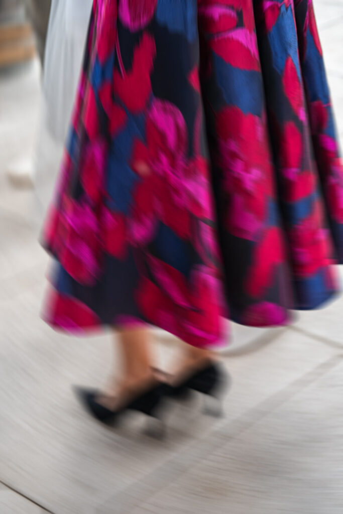 Editorial-Detailaufnahme eines Rocks mit rot-blau-pinkem Blumenmuster in Bewegung, Bewegungsunschärfe als Stilmittel