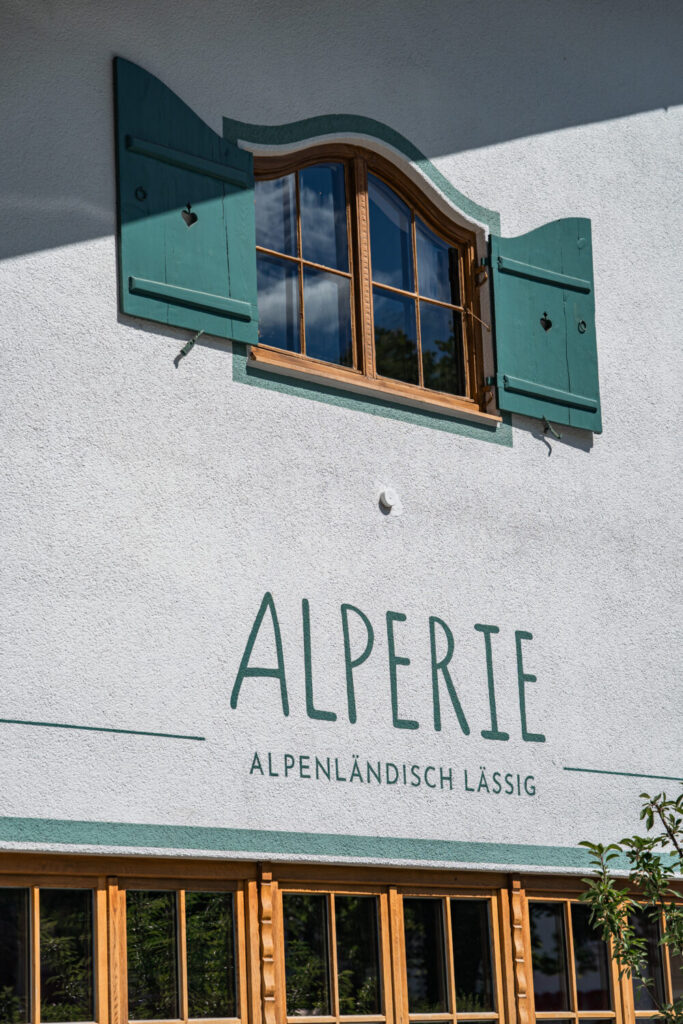 Fassadendetail der Hochzeitslocation Alperie mit grünen Fensterläden und alpenländischem Fachwerk-Fenster